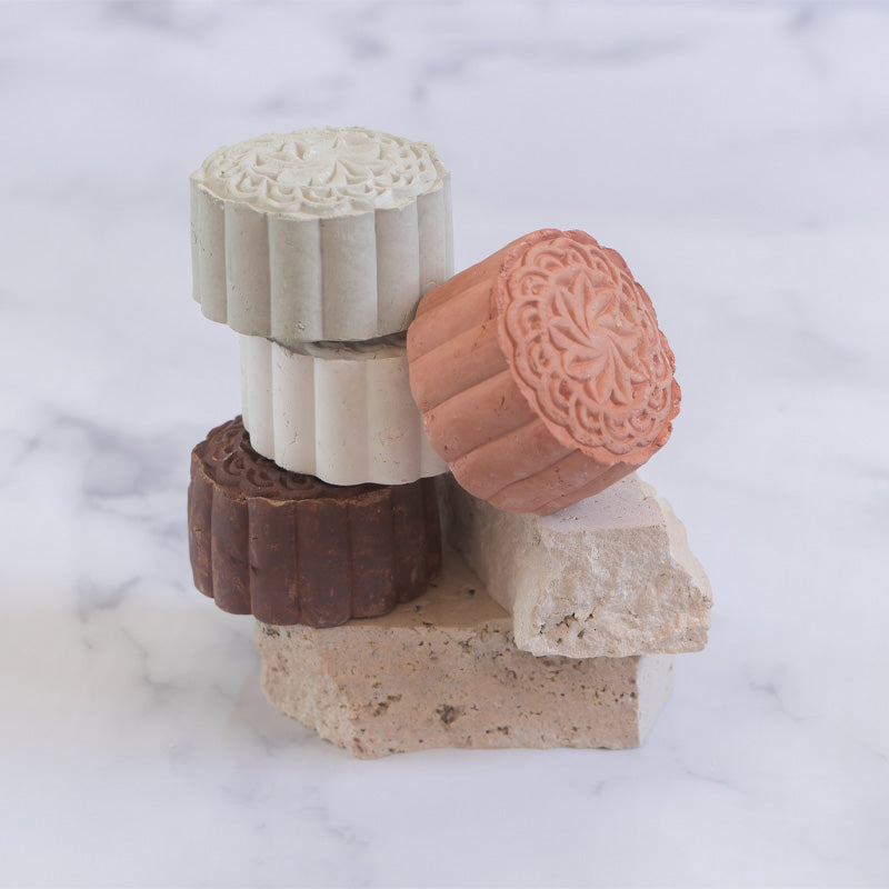Modani Naturals Face Clay Mask Bars stacked together on stone pedestal with marble background.