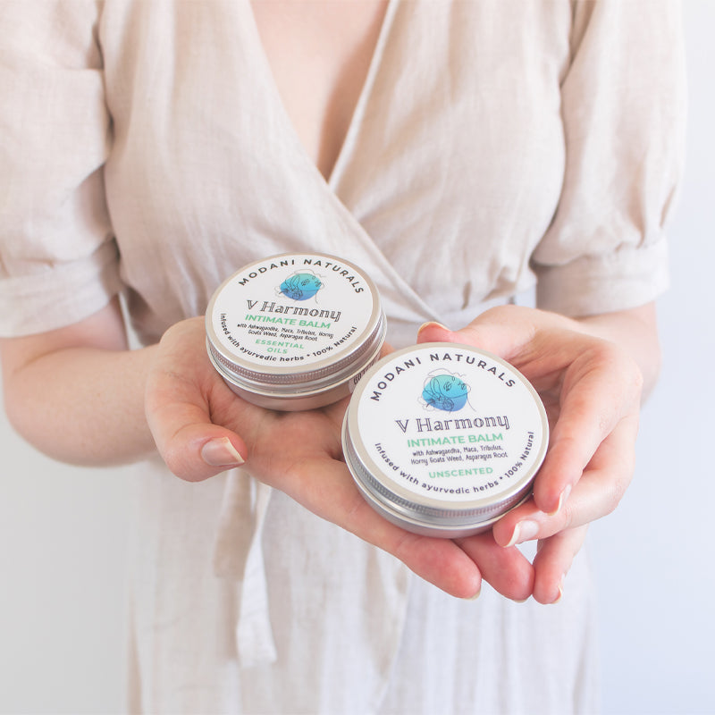 Woman holding 2 tins of Modani Naturals V Harmony Intimate Balm
