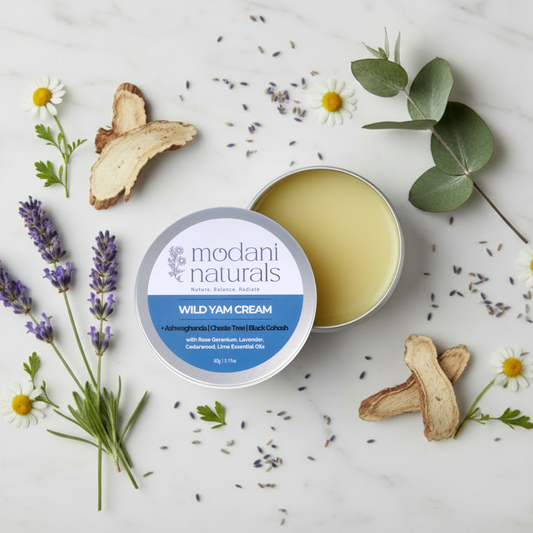 Open tin of modani naturals wild yam cream with label showing and scattered botanicals surrounding the tin. 