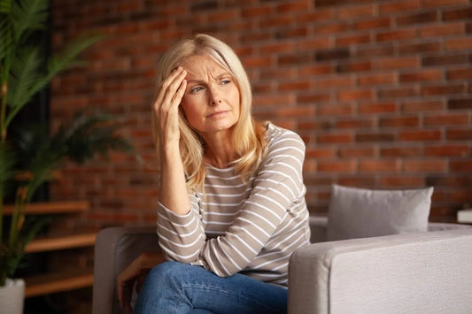 Middle-aged woman looking confused and fatigued, sitting on a couch, representing menopause brain fog