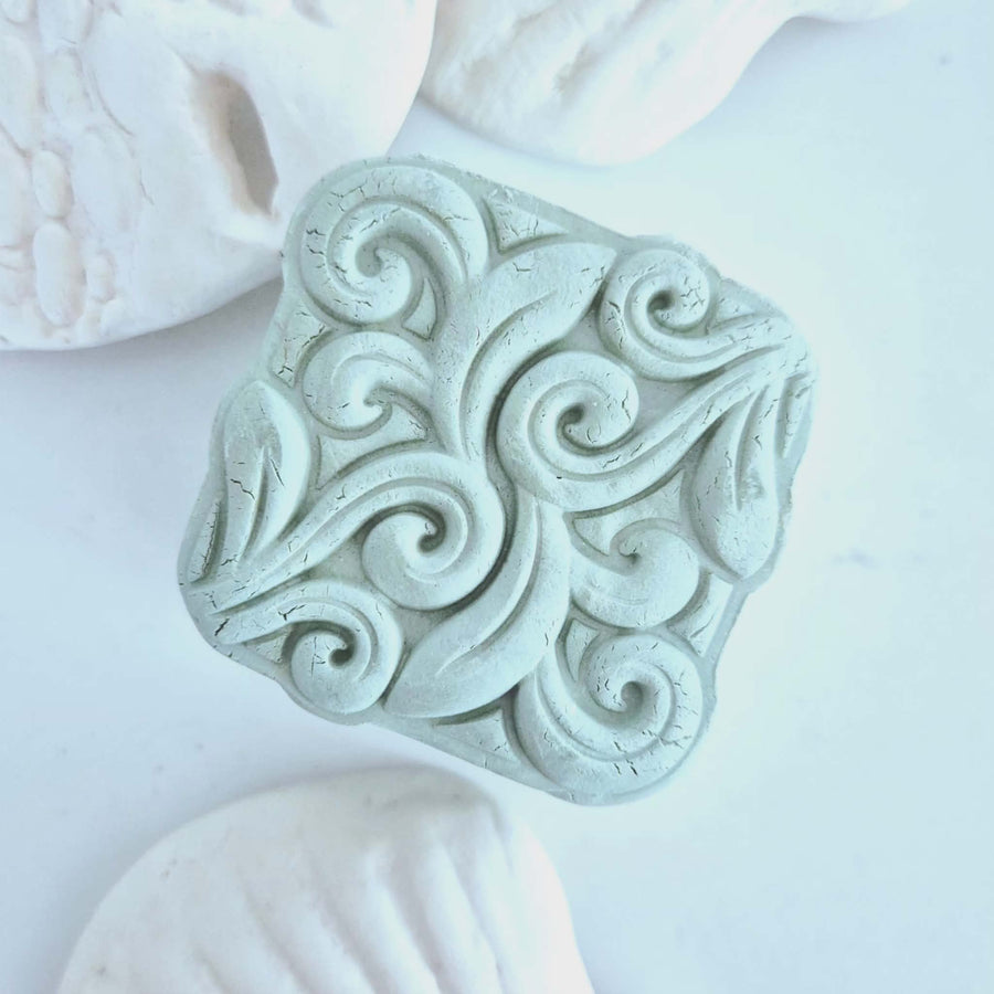 Textured blue clay stone mask bar with swirled top surface. 