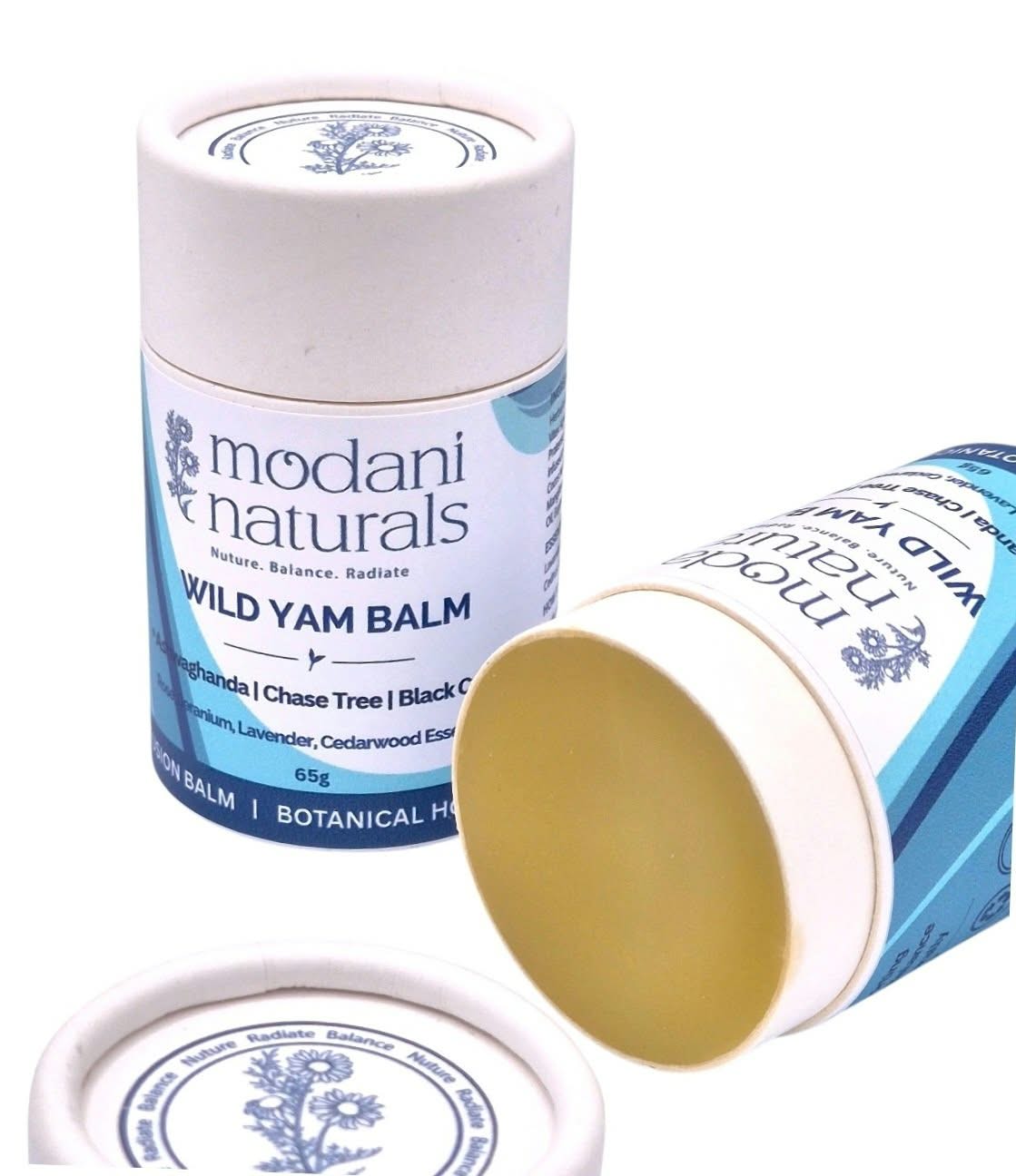 Modani Naturals Wild Yam Balm shown in its white and blue cylindrical cardboard packaging, with one tube standing upright, another lying on its side showing the pale yellow balm inside, and a separate lid in the foreground on a white background.