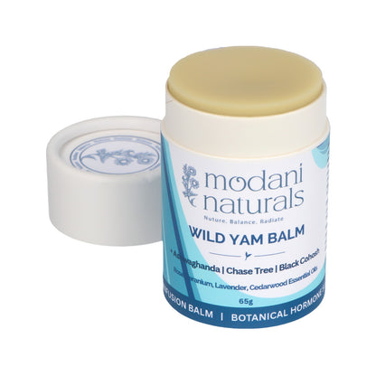 A cardboard push up tube of Modani Naturals Wild Yam Balm showing contents inside with its white lid placed beside it on a clean white background.
