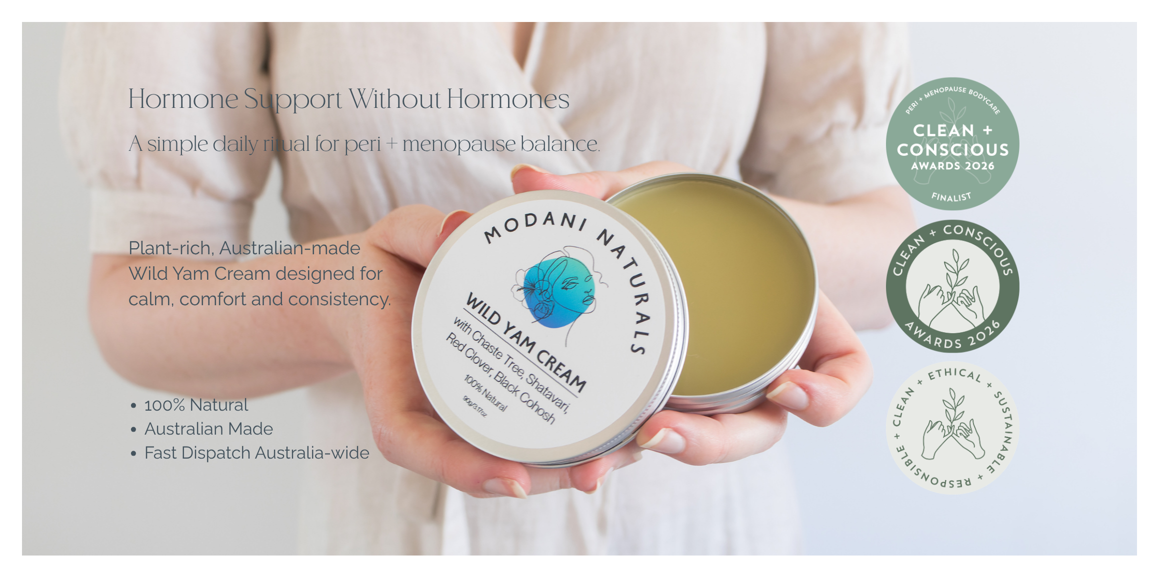 Person holding a container of Modani Naturals Wild Yam Cream with product details on a light gray background.