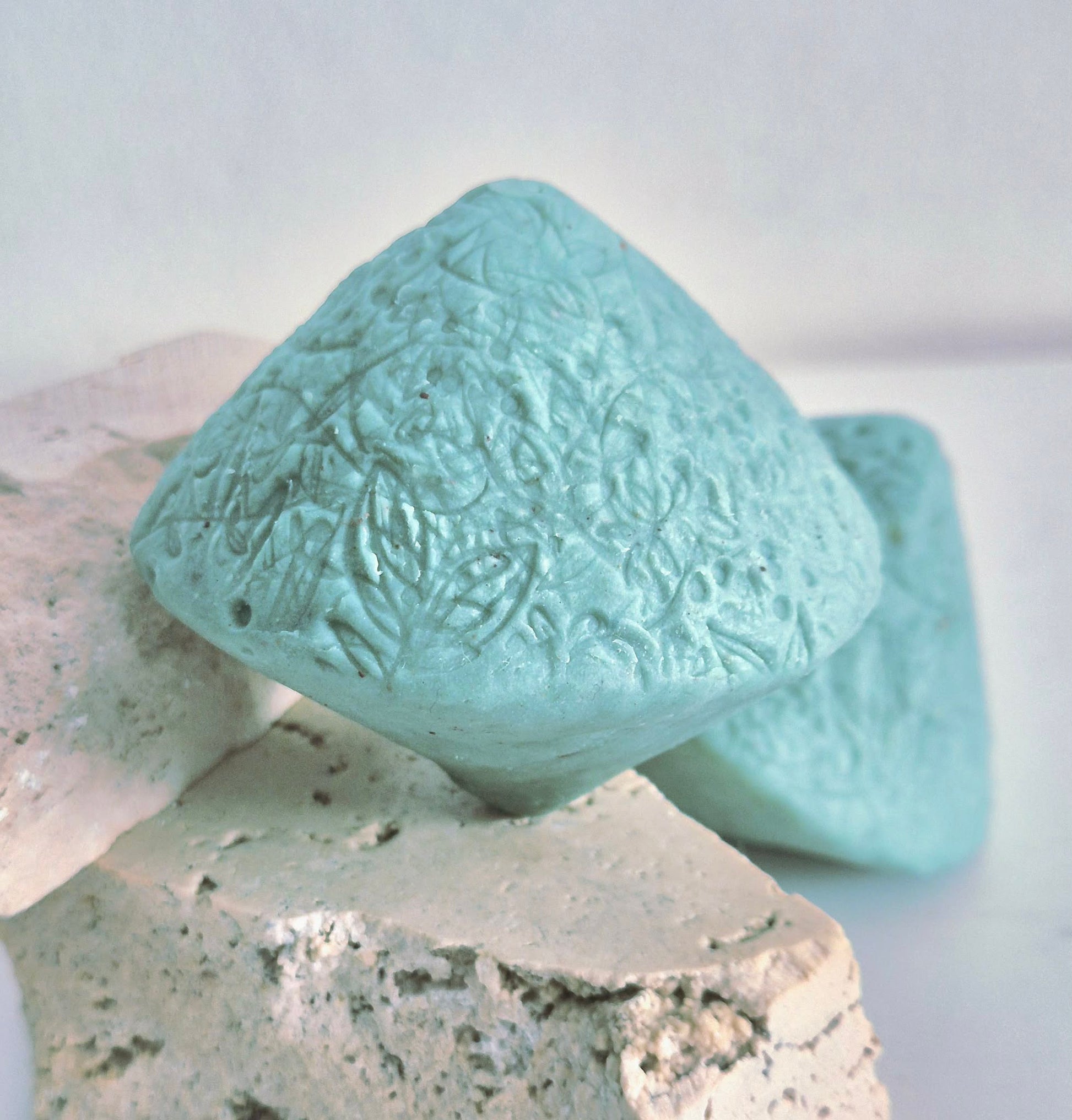 Teal textured ocean beauty stone bar on a stone surface with a white background