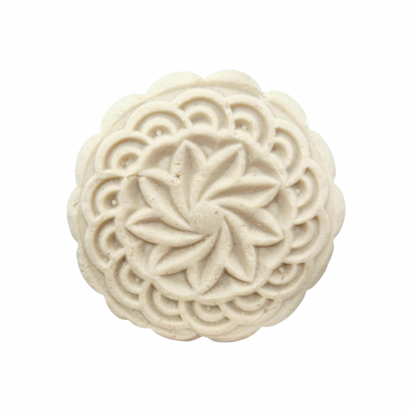 Decorative white solid shampoo bar with intricate carvings on a white background