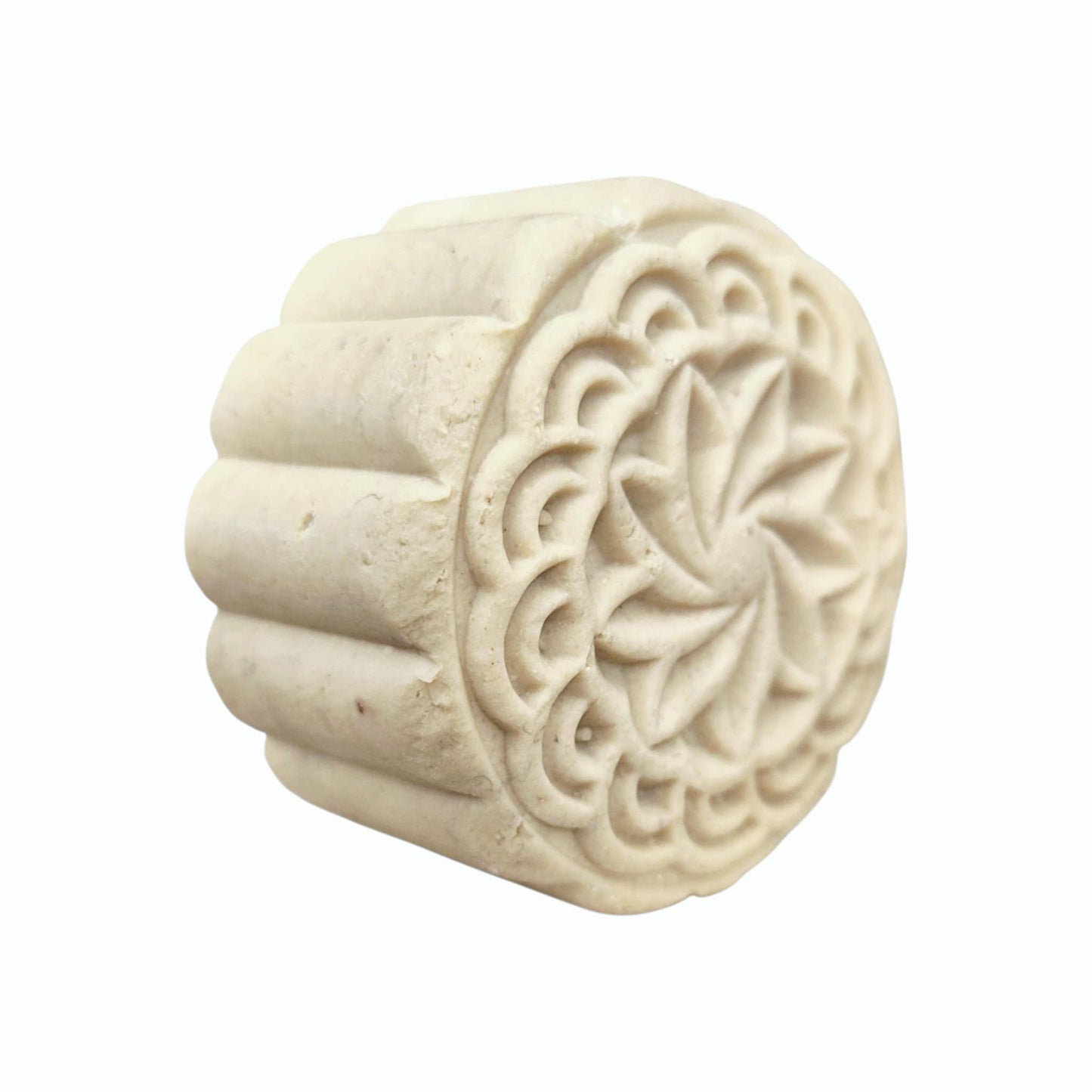 Decorative white solid shampoo bar with intricate carvings on a white background