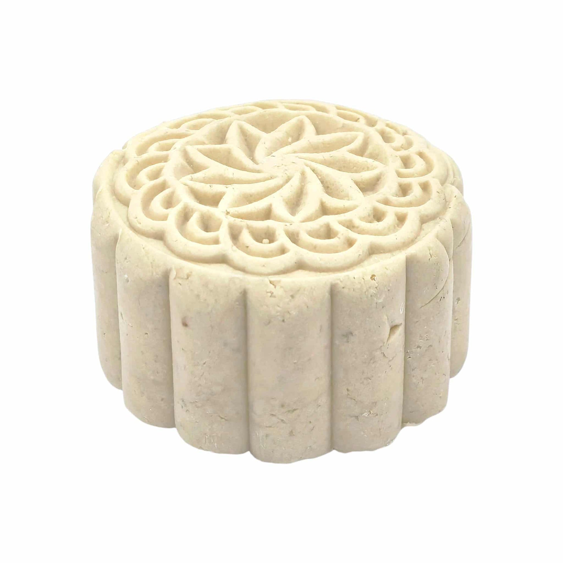 Decorative white solid shampoo bar with intricate carvings on a white background with eye view. 