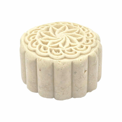 Decorative white solid shampoo bar with intricate carvings on a white background with eye view. 